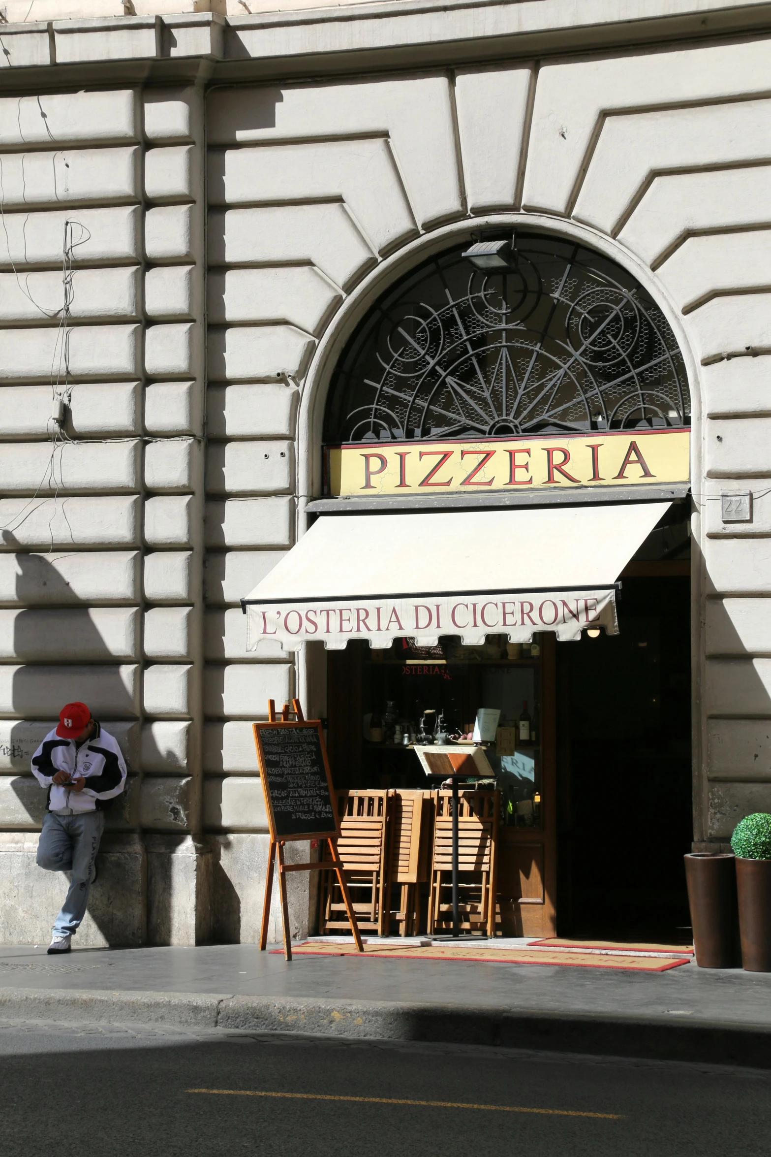 man sitting on the sidewalk of an italian restaurant