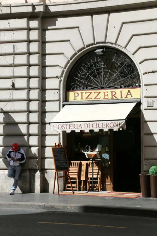 man sitting on the sidewalk of an italian restaurant