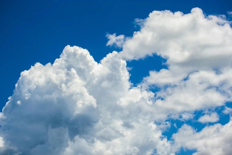 an airplane flying through a cloud filled blue sky