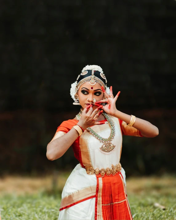 a woman wearing traditional indian attire in front of green grass