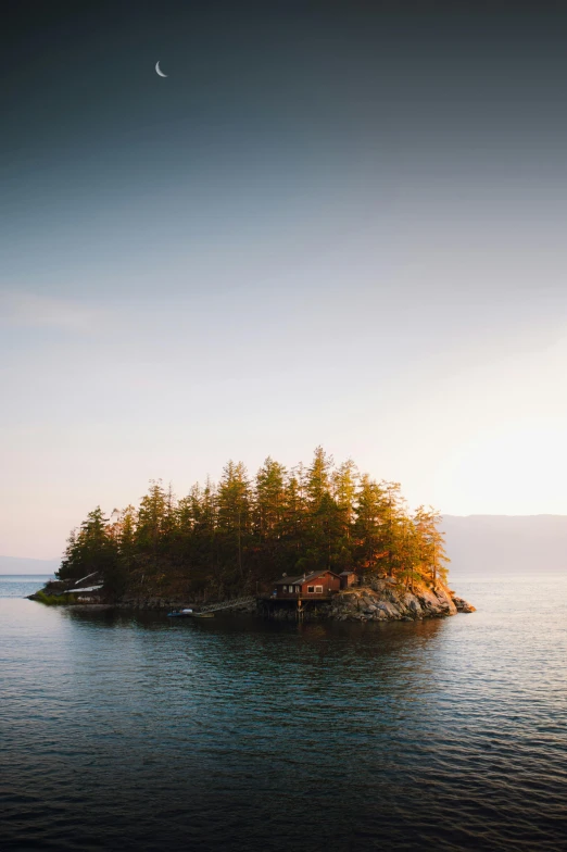 small island with trees and boat in ocean at dusk