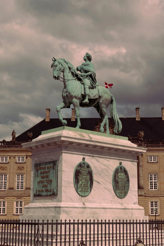 the equestrian statue is near a fence on a cloudy day