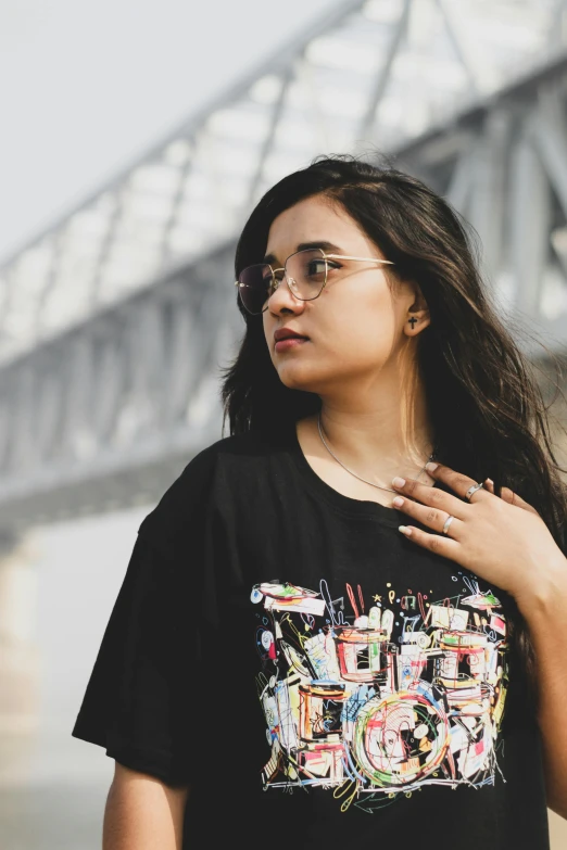 a young woman wearing glasses is standing on the riverbank