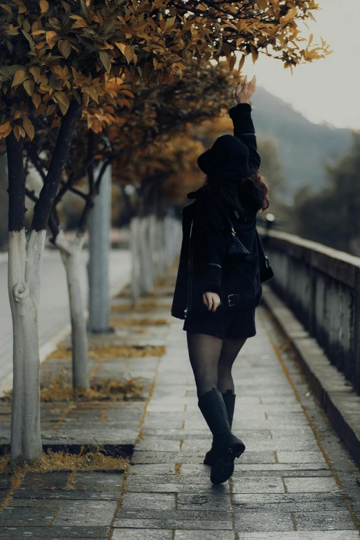 the woman is walking down the sidewalk wearing a black jacket