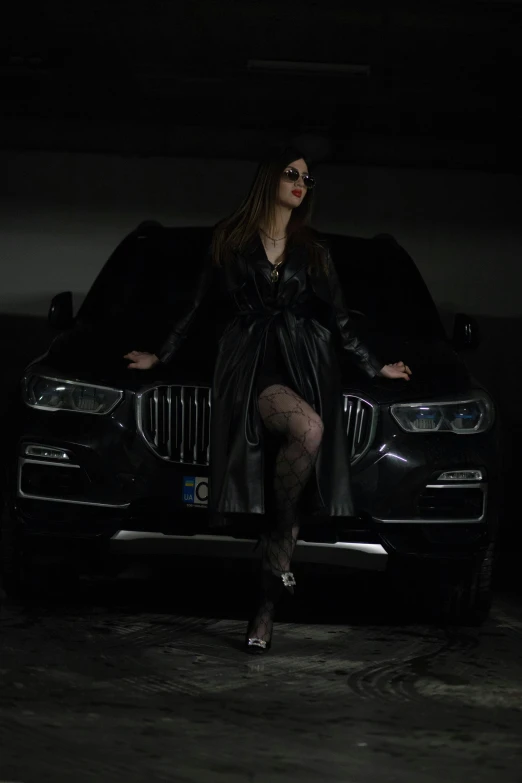 the woman in the black dress is posing beside her car
