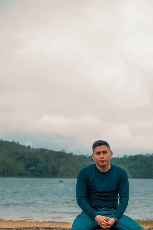 a man in blue shirt sitting on top of a rock