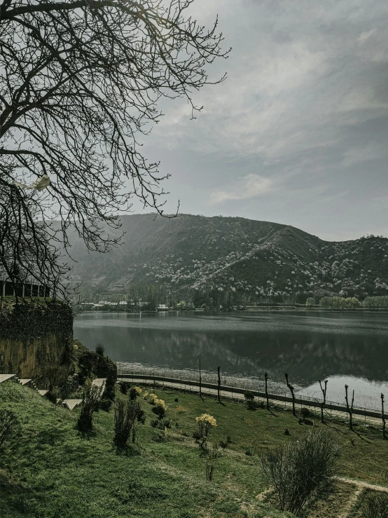 a lake on a cloudy day in front of a green hillside