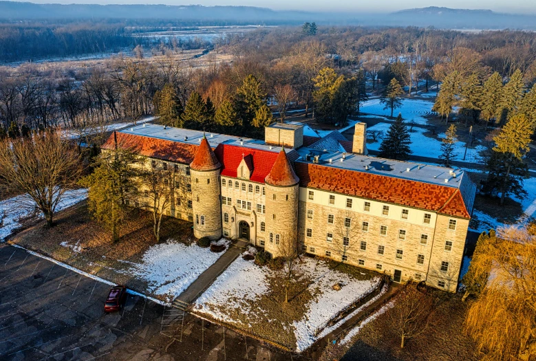 an old building with red tiles is surrounded by snowy trees