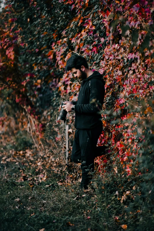 a man standing in front of colorful plants with his camera