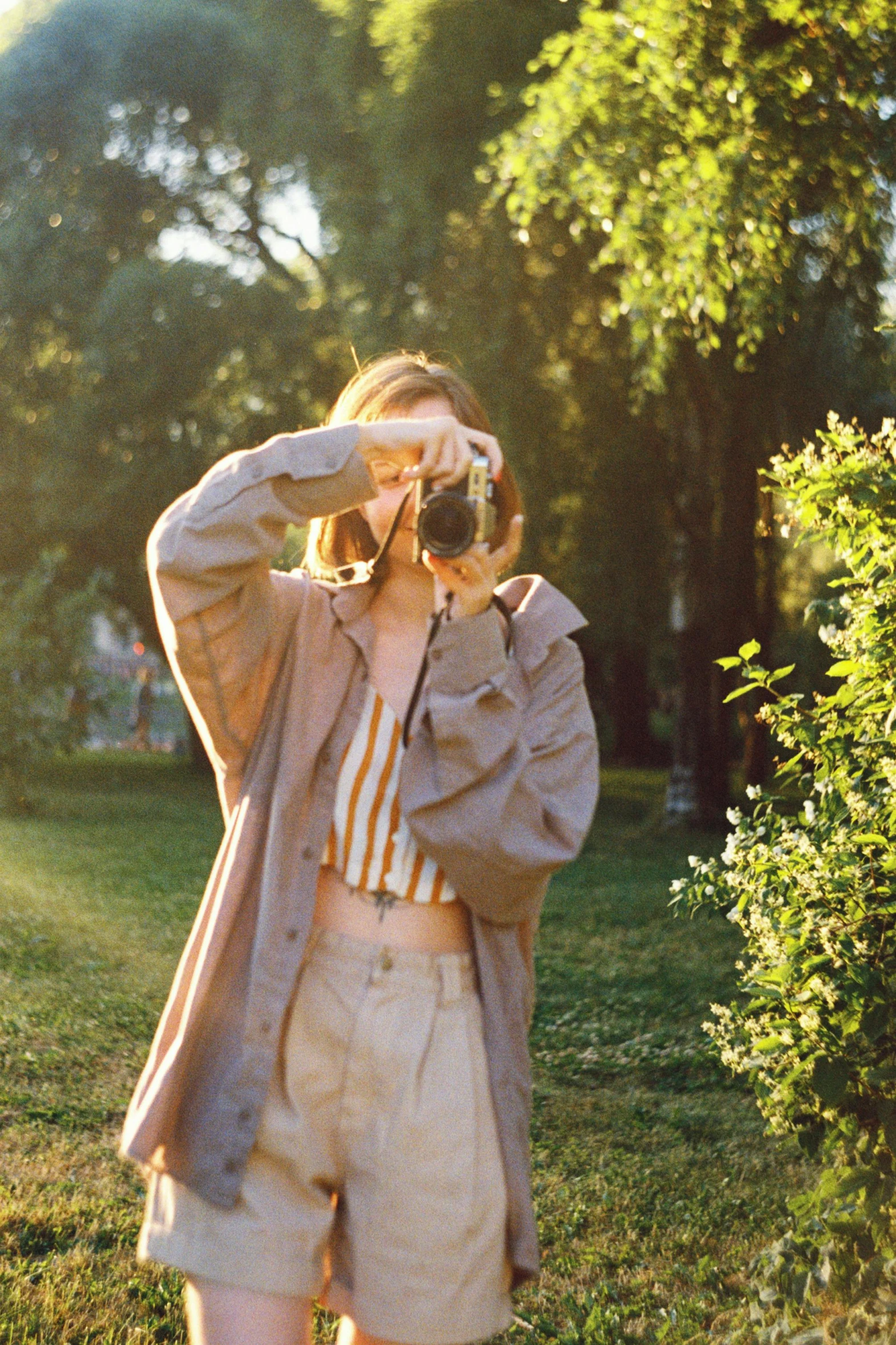 a woman standing on a field taking a po with her camera