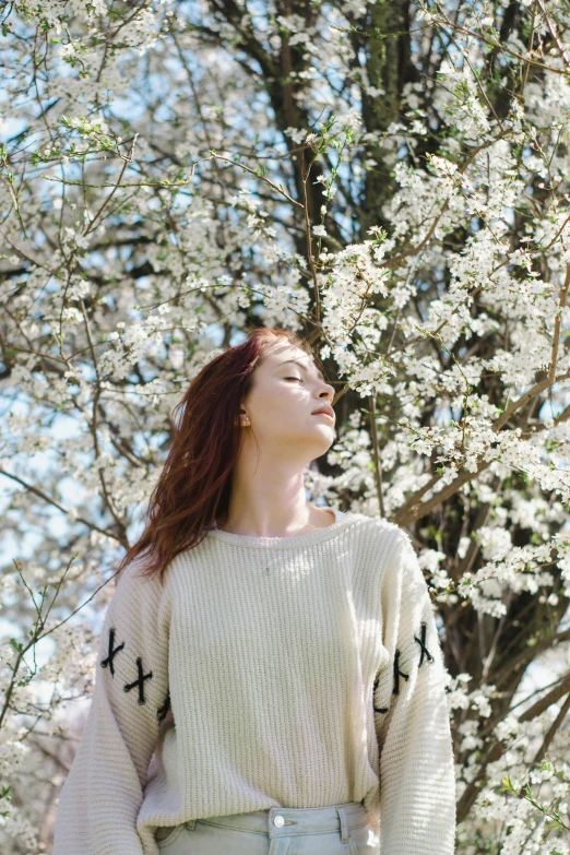 the girl is looking up while wearing a sweater