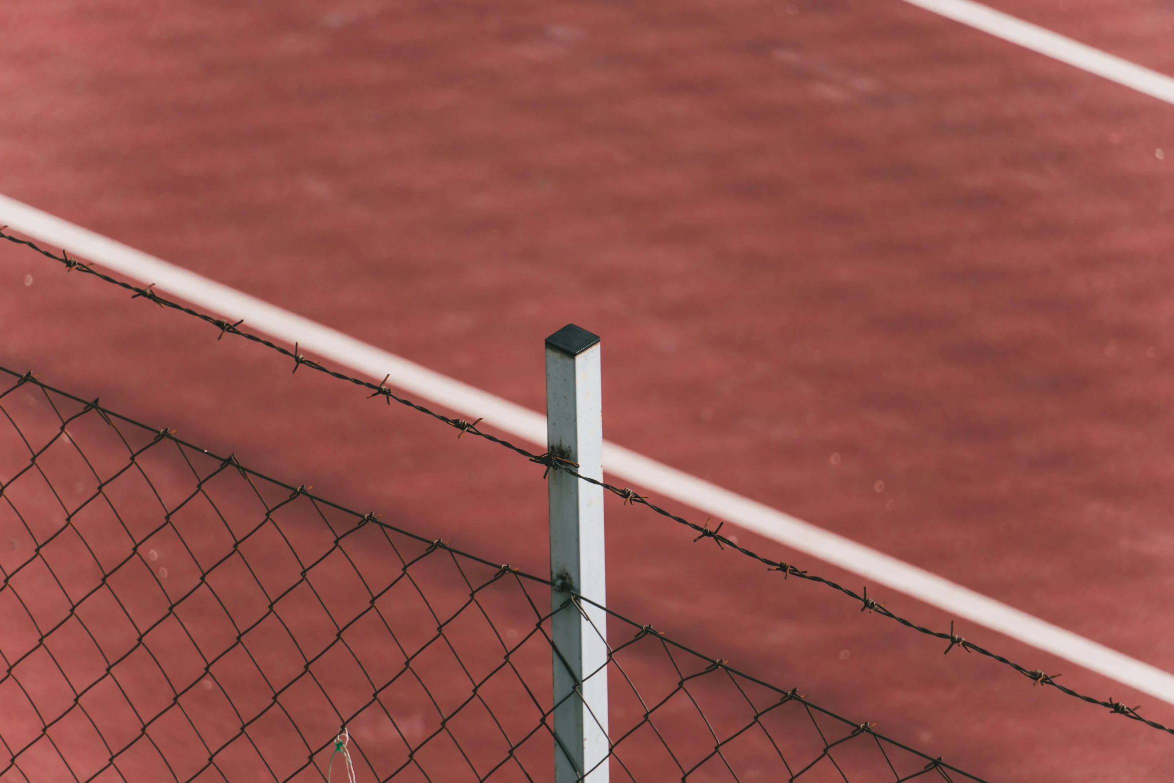 a tennis court with a metal fence is empty