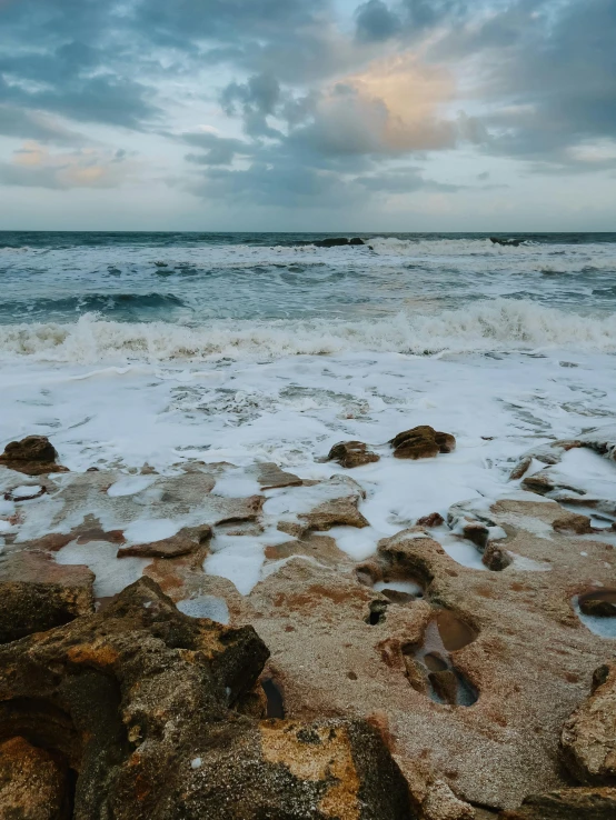 ocean scene with rocks, stormy sky, and white clouds