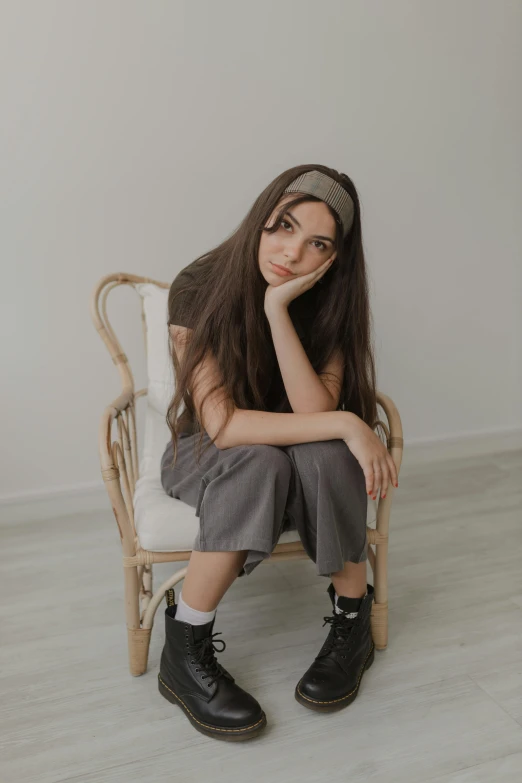 a woman sitting in a chair with her hand under her chin and head