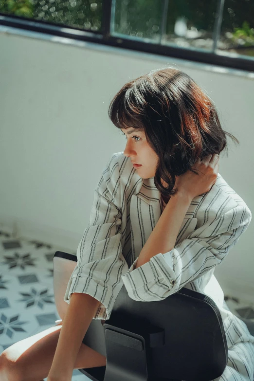 young lady sitting in a chair next to the window