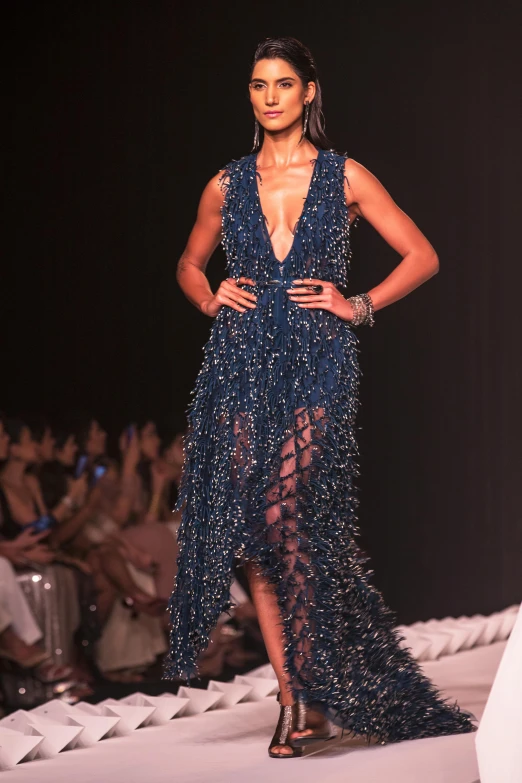 a model wearing a blue beaded gown and thigh high boots