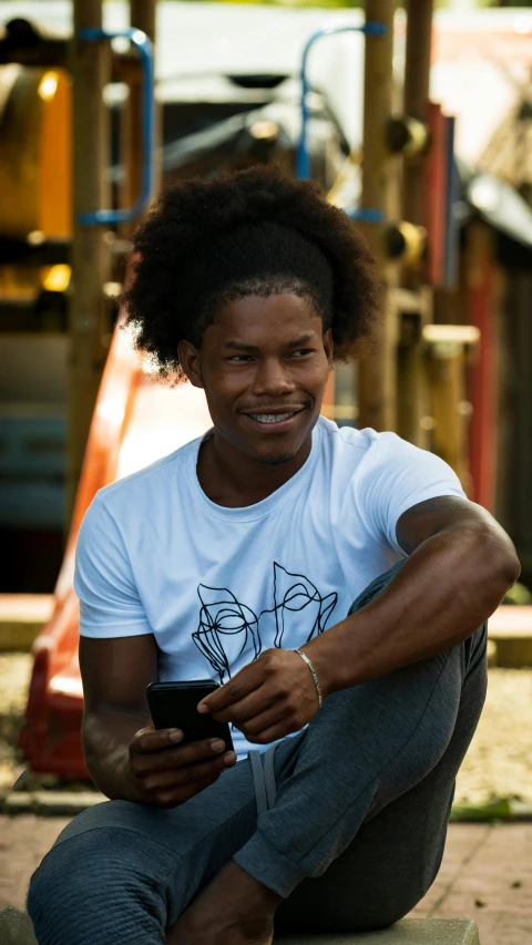 a smiling black man holds his cell phone