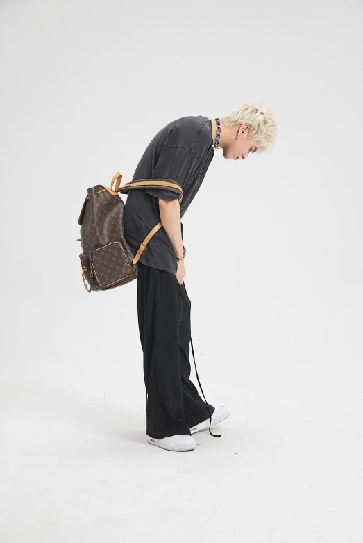 a blond man holding a brown purse and wearing white sneakers