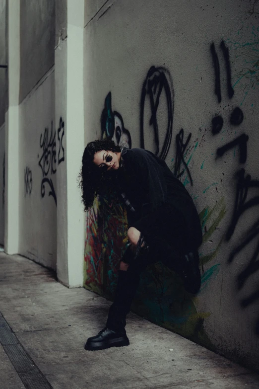 an image of woman leaning on wall posing for camera