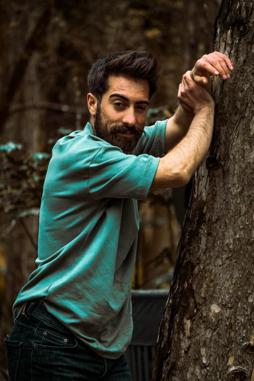 a man with a beard standing next to a tree