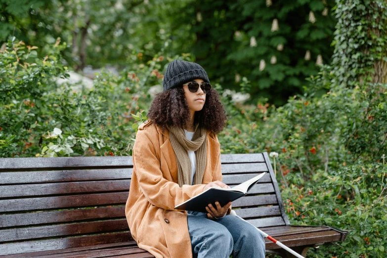 a woman sits on a bench, holding an open book