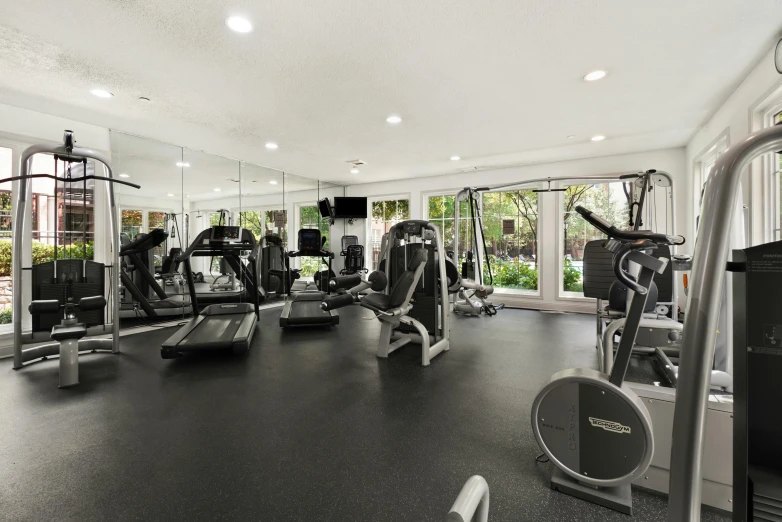 a gym with equipment, mirrors and a door