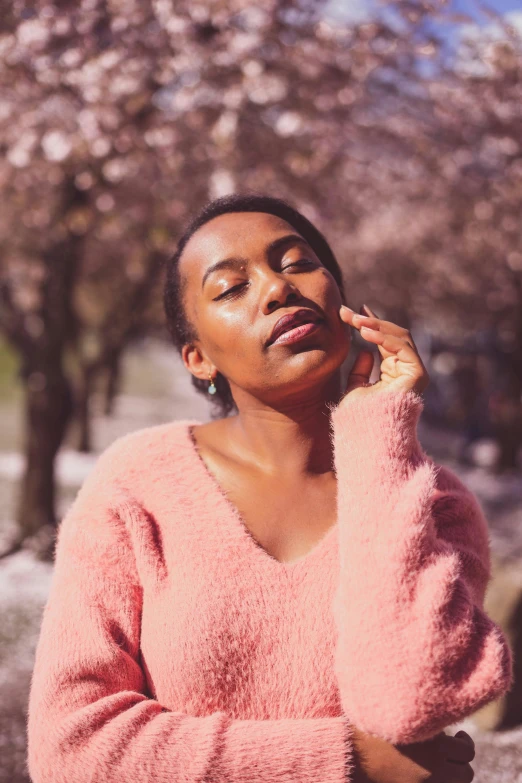 a young woman standing in front of blossom covered trees