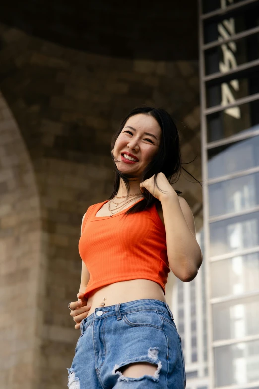 a girl in an orange shirt smiles as she stands outside