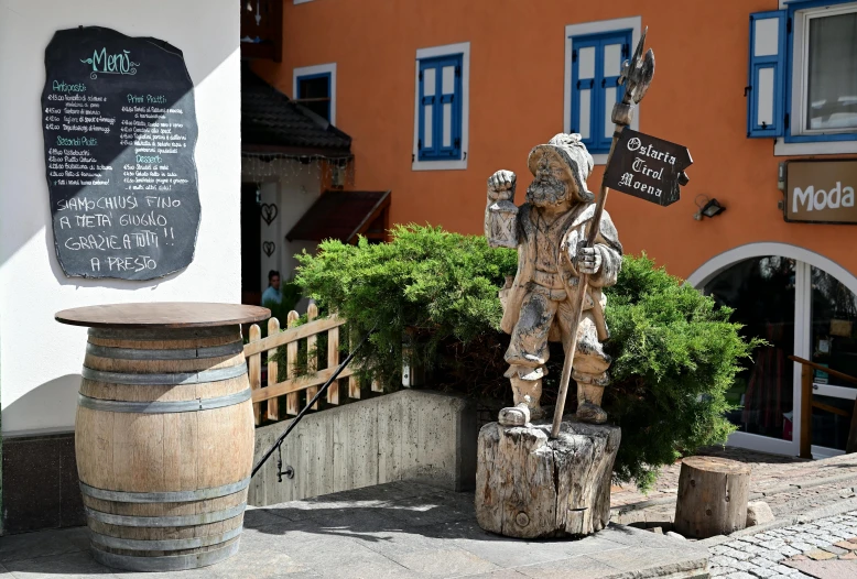 a statue stands next to some barrels near a building