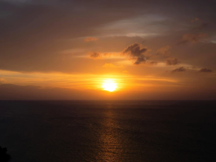 the sun setting over the ocean from a cliff