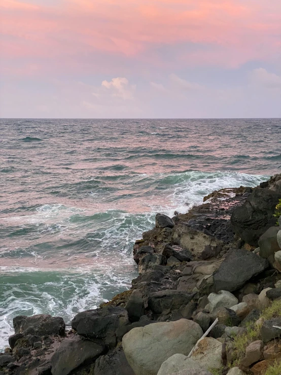 a beach that has waves in it and rocks on the shoreline