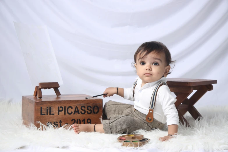 a baby is posed with a piece of luggage