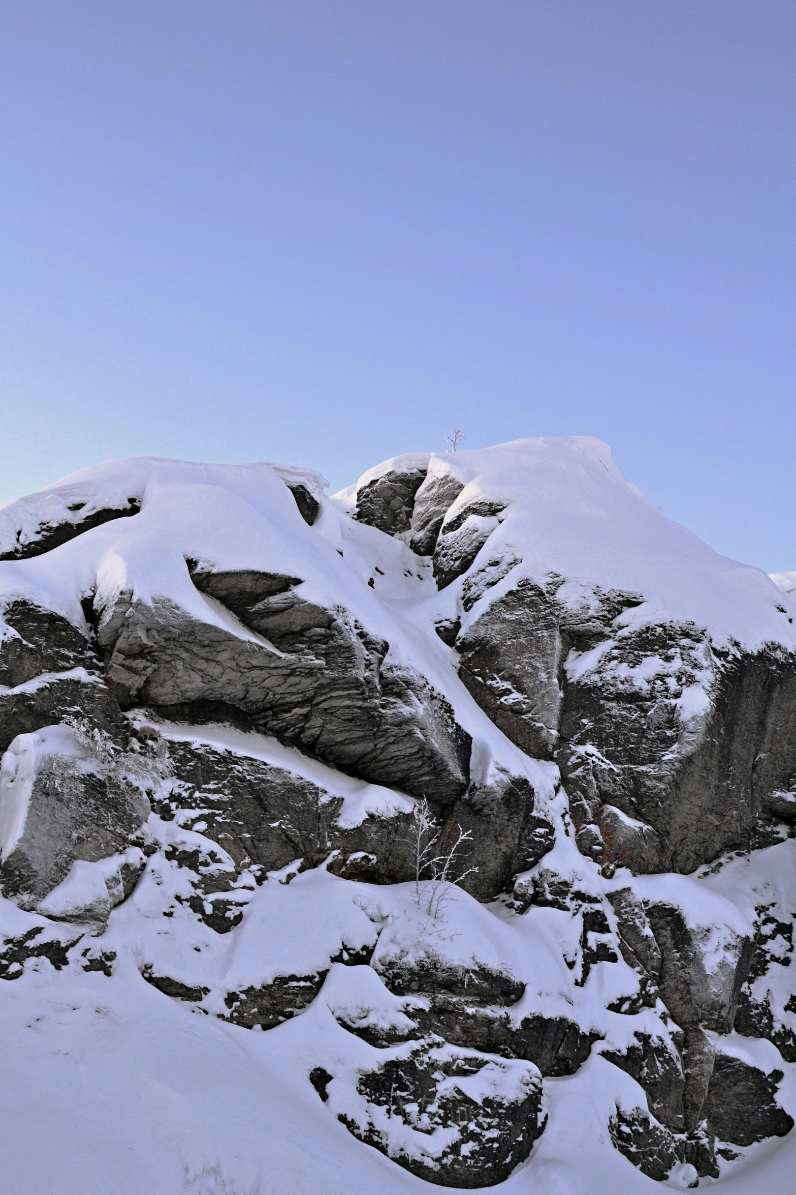 a snowboarder stands at the base of a snowy mountain