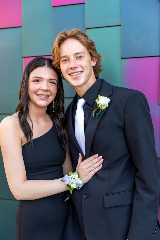 a young man and woman standing together outside of a building