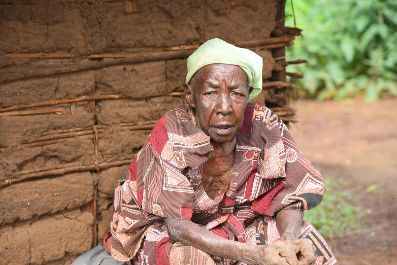 an old woman with a green turban holding a piece of food