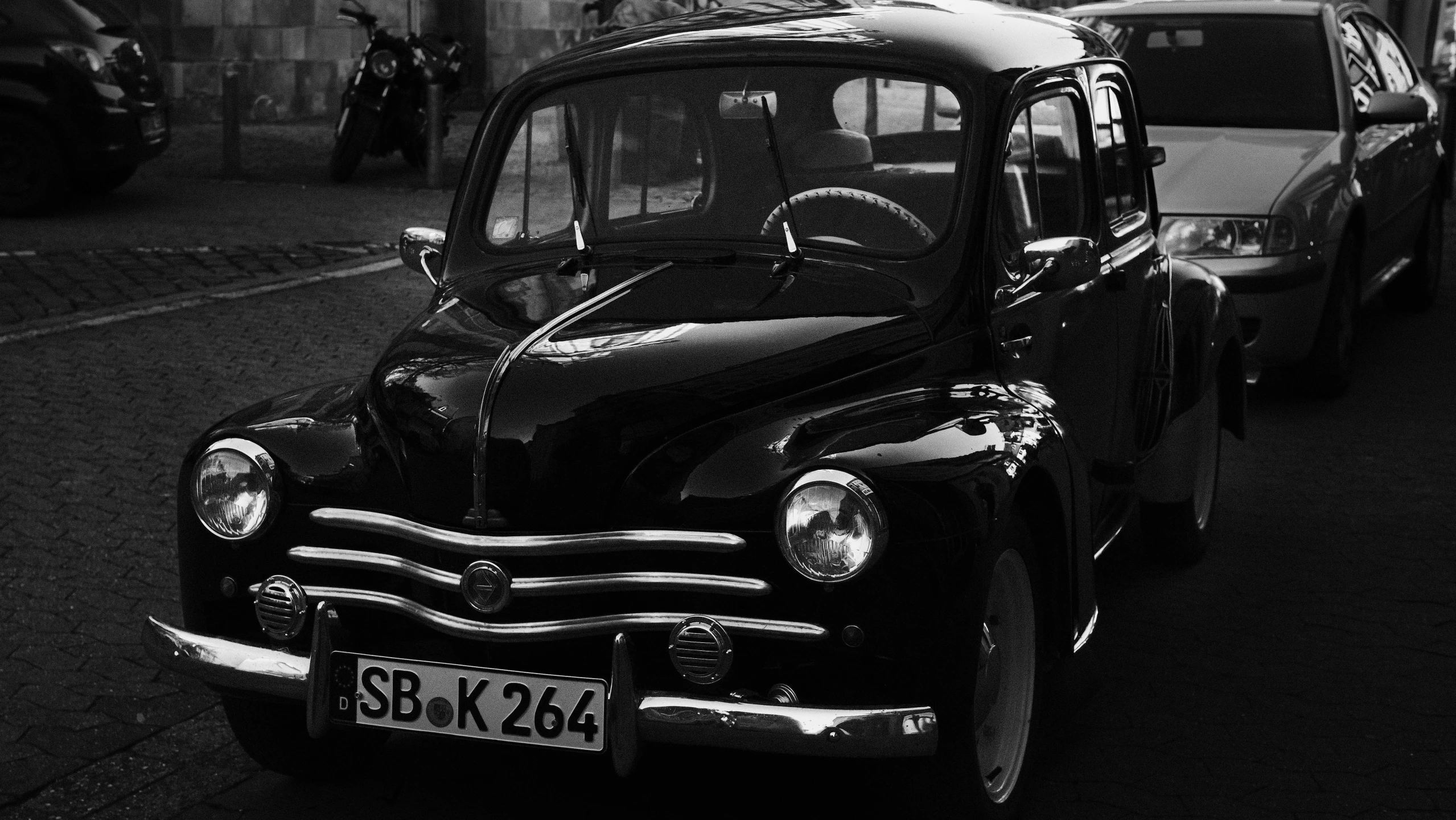 a black car on street next to a motorcycle