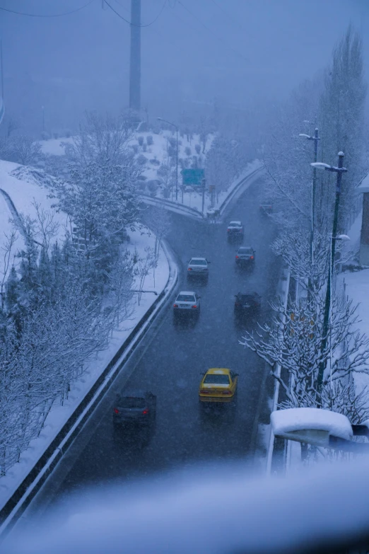 a snowy street is full of traffic and trees