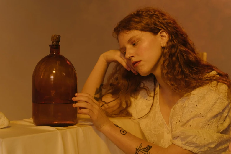 a girl sitting down next to a brown bottle