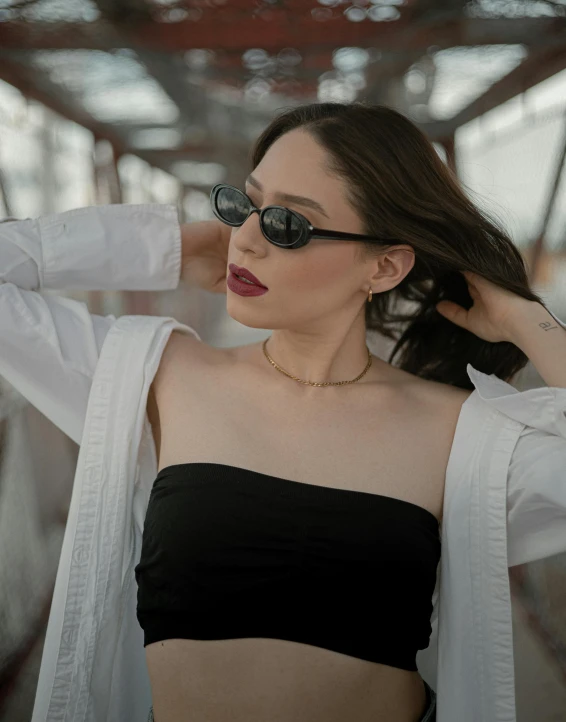 young woman posing outdoors wearing sunglasses and a black top