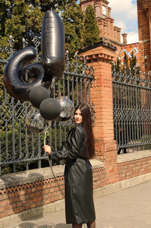 woman holding balloons in her hands outside near a fence