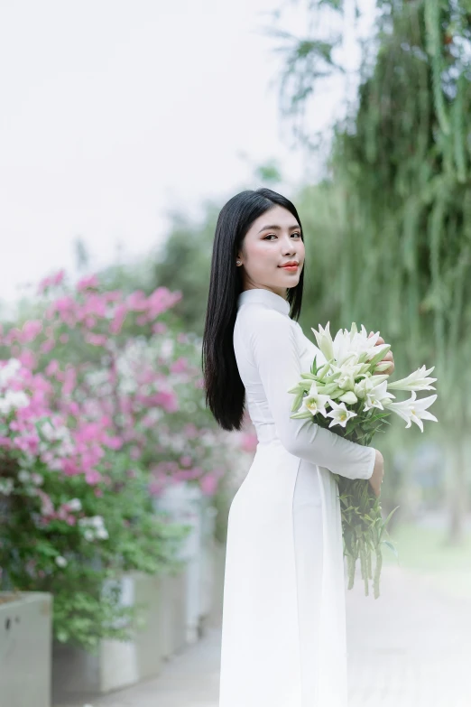 a woman is holding flowers and standing outside