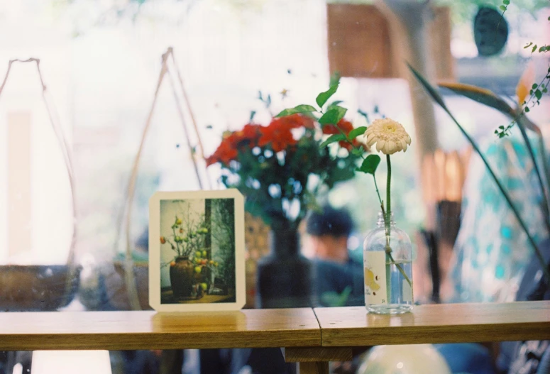 a table that has a vase with flowers and picture