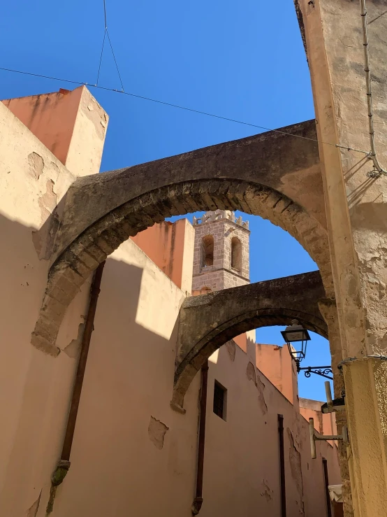 some buildings and two bells are seen through the archways