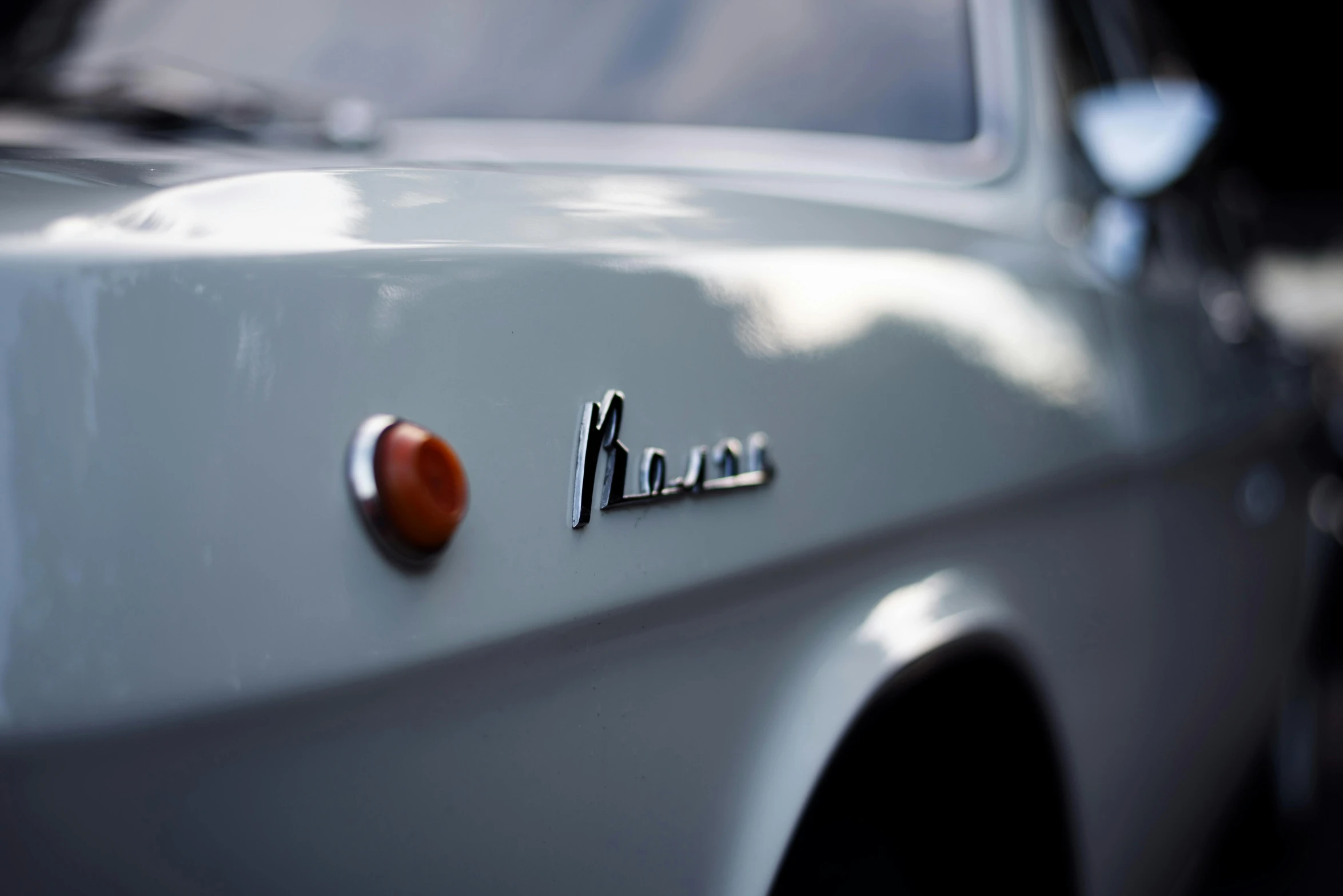 an old car with chrome lettering sitting in the shade