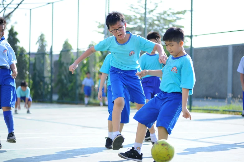 children playing soccer on an outdoor court with a referee