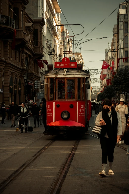 a red trolley is on a track through some buildings