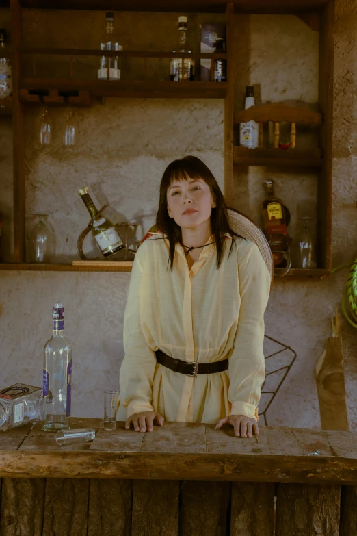 a woman standing at a table behind some liquor