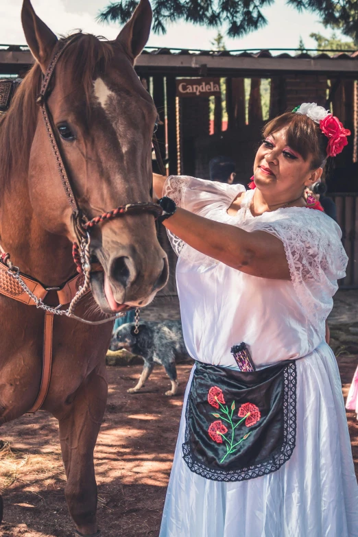 a woman stands by a horse wearing a head dress