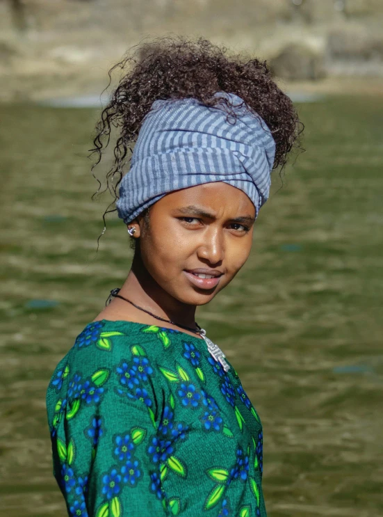 young woman with a blue and green top with head scarf on