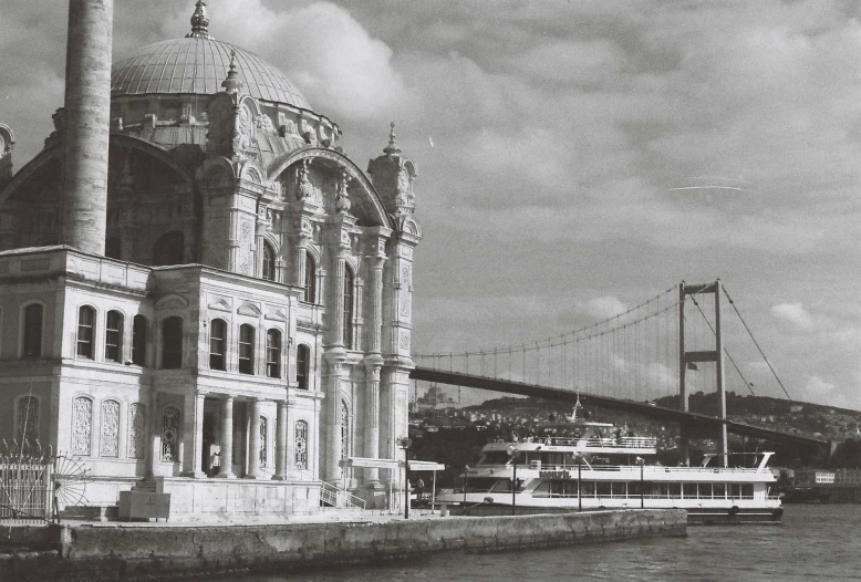 the building has an ornate roof and is on the side of the river